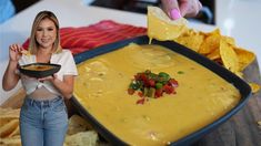 a woman is holding a bowl of quesadilla dip with tortilla chips