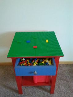 a table with legos on it in the middle of carpeted floor next to wall