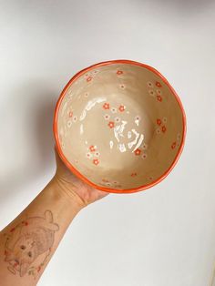 a person's arm holding an orange and white bowl with a bear on it