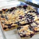 blueberry crumble pie cut into slices on a plate