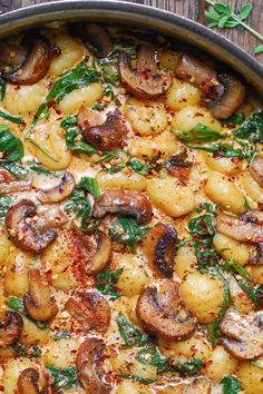 a pan filled with pasta and mushrooms on top of a wooden table