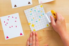 someone is cutting out paper with scissors on a wooden table next to some crafting supplies