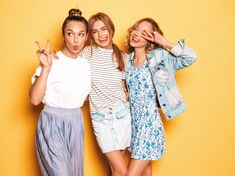 three young women standing next to each other and making the peace sign with their hands