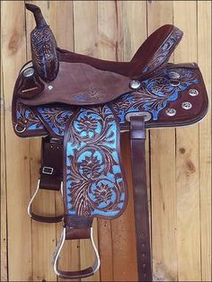 a brown and blue horse saddle sitting on top of a wooden floor