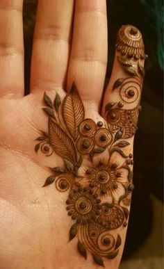 a person's hand with a henna on it and some flowers in the middle