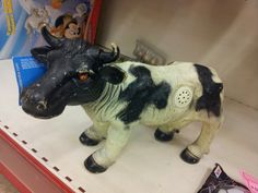 a black and white cow figurine is on display in a toy store shelf