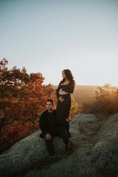 a man and woman sitting on top of a rock