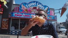 a man sitting at a table eating a doughnut in front of an ice cream shop