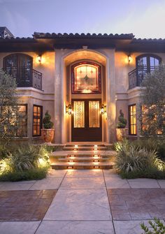 a large house with steps leading up to the front door and lights on either side