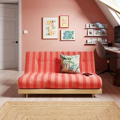 an orange and white striped couch sitting in front of a computer desk