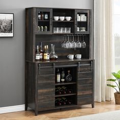 a wooden bar with wine glasses and liquor bottles on the top, in front of a window