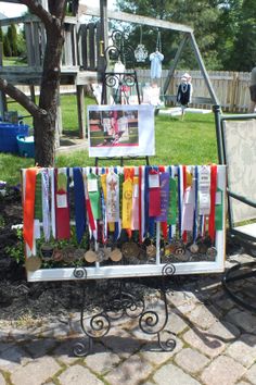 an iron bench with medals hanging from it's sides in front of a tree