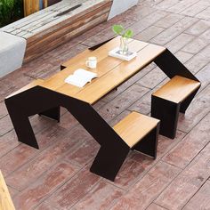 a wooden table sitting on top of a brick floor next to a planter filled with flowers