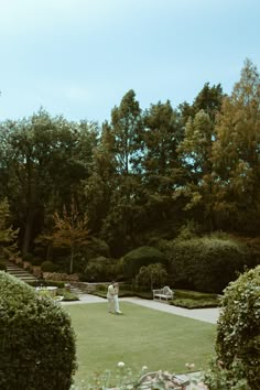 a bride and groom are standing in the middle of a formal garden with lush greenery