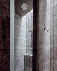 a bathroom with tiled walls and flooring next to a shower head mounted on the wall