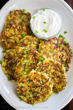 some food is on a white plate with a small bowl of ranch dressing next to it