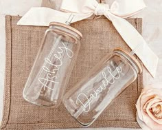 two personalized mason jars are sitting on a burlock with a white ribbon