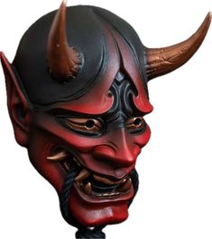 a red and black mask with horns on it's head is shown in front of a white background