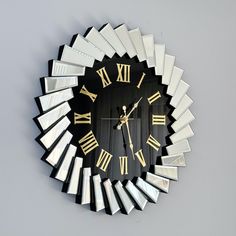 a black and gold clock with roman numerals on the face is hanging on a wall