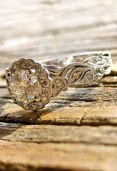 an engagement ring is sitting on top of a piece of wood