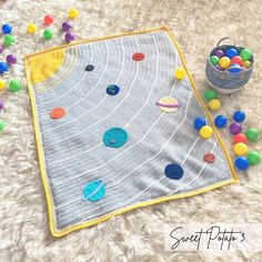 a crocheted blanket with colorful balls on it next to a bowl of candy