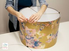 a woman is holding a lamp shade on the table