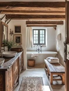 a bathroom with a tub, sink and wooden beams on the ceiling in front of a window