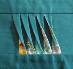 four pieces of cloth are folded together on a piece of blue fabric with multicolored dots