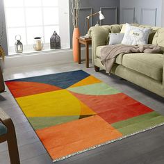 a living room with a green couch and colorful area rugs on the floor in front of a window