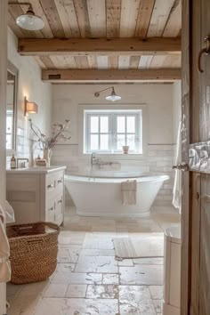 a white bath tub sitting inside of a bathroom next to a sink and toilet under a window