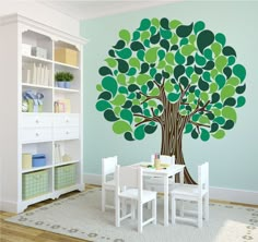 a child's room with a tree wall decal on the wall and white furniture