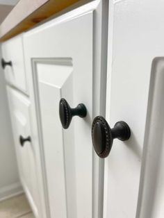 a close up of a door handle on a white cabinet in a kitchen with tile flooring