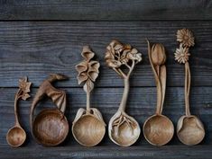 wooden spoons lined up in a row with flowers and leaves carved into the sides