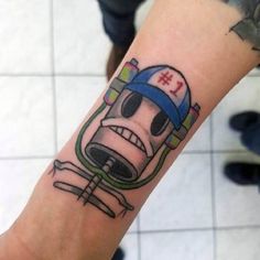 a person with a tattoo on their arm that has a cartoon character wearing a hat