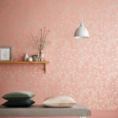 a room with pink wallpaper and pillows on a bench next to a shelf filled with vases