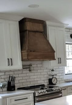 a kitchen with white cabinets and stainless steel stove top oven in the middle of it