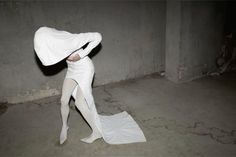 a woman dressed in white standing on top of a sheet