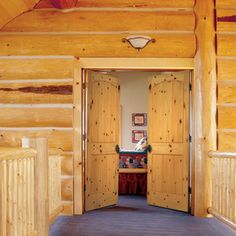 the inside of a log cabin with wooden walls and doors leading to an entry way