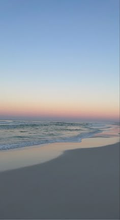 an empty beach with waves coming in to the shore