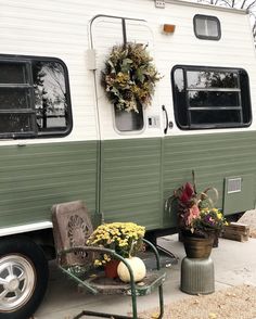 an old camper is decorated with wreaths and potted plants on the front porch