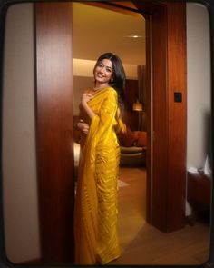 a woman in a yellow sari poses for the camera