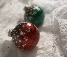 two red and green ornaments sitting on top of white paper