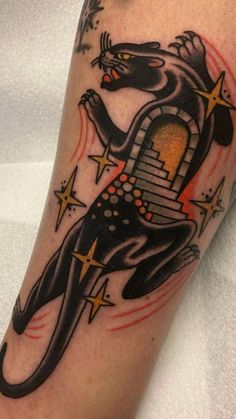 a tattoo on the leg of a person with a black cat and stars around it