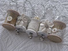 four small spools with bows and pearls on them sitting on a white tablecloth