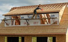 a man standing on the roof of a house under construction