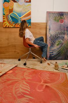 a woman sitting on a chair in front of some art work with her back to the camera