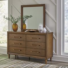 a dresser with two vases and a mirror on it