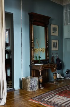 a room with blue walls and wooden flooring has a large mirror on the wall