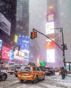 a city street filled with lots of traffic covered in snow and surrounded by tall buildings