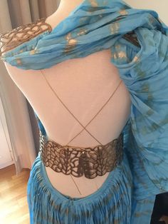 a mannequin is wearing a blue dress with an intricate design on the back